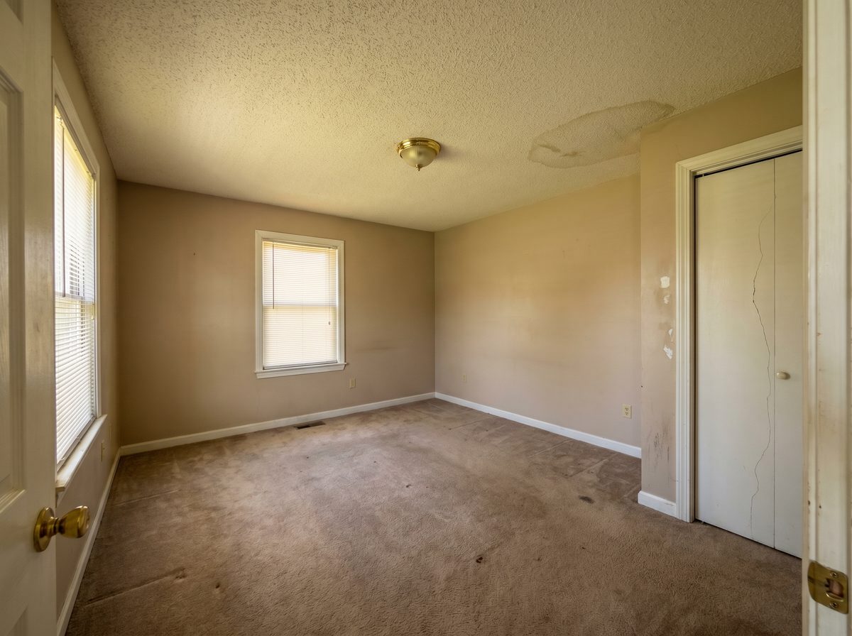 Dated master bedroom with beige walls and popcorn ceiling — before professional repaint
