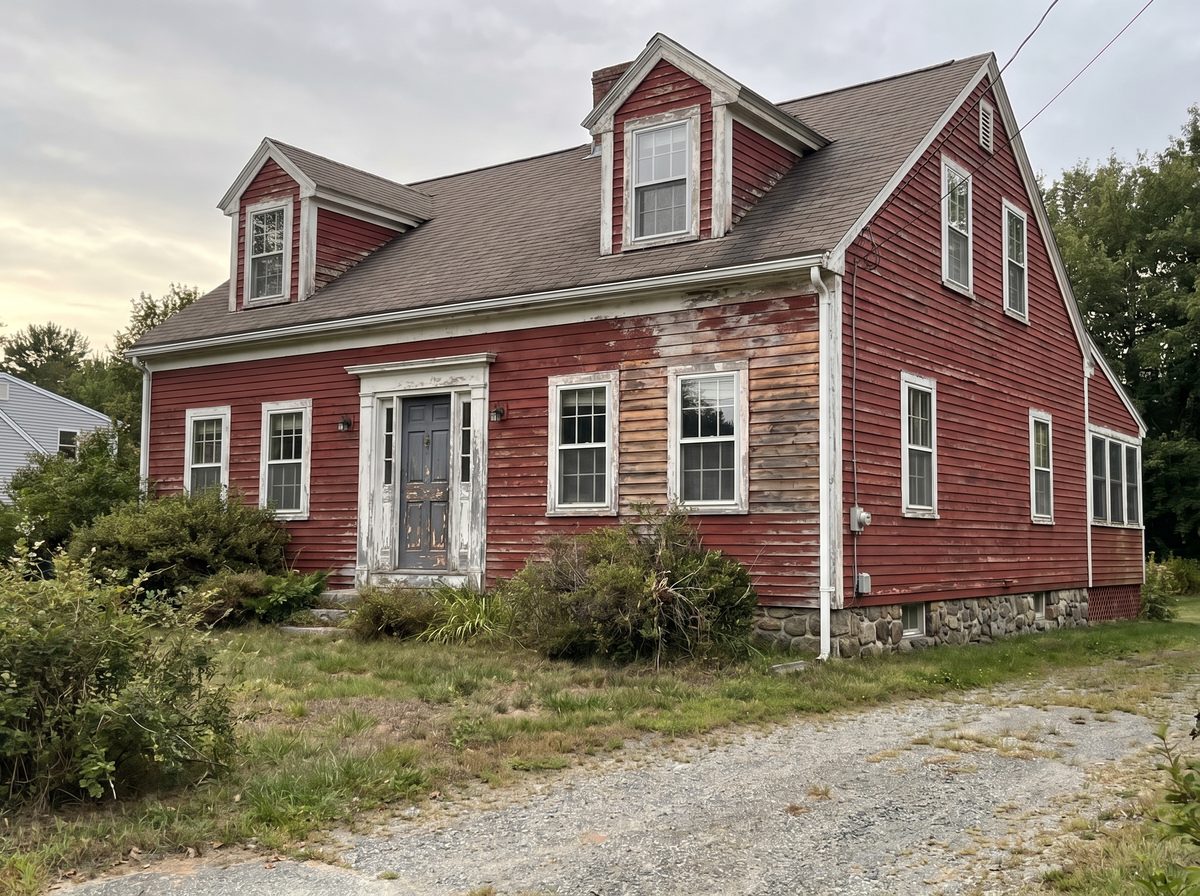 Weathered Cape Cod home with peeling red paint in Litchfield NH — before exterior repaint